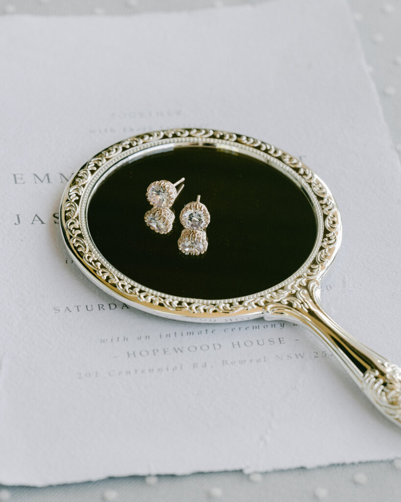 The White Collection bridal stud earrings on a hand mirror