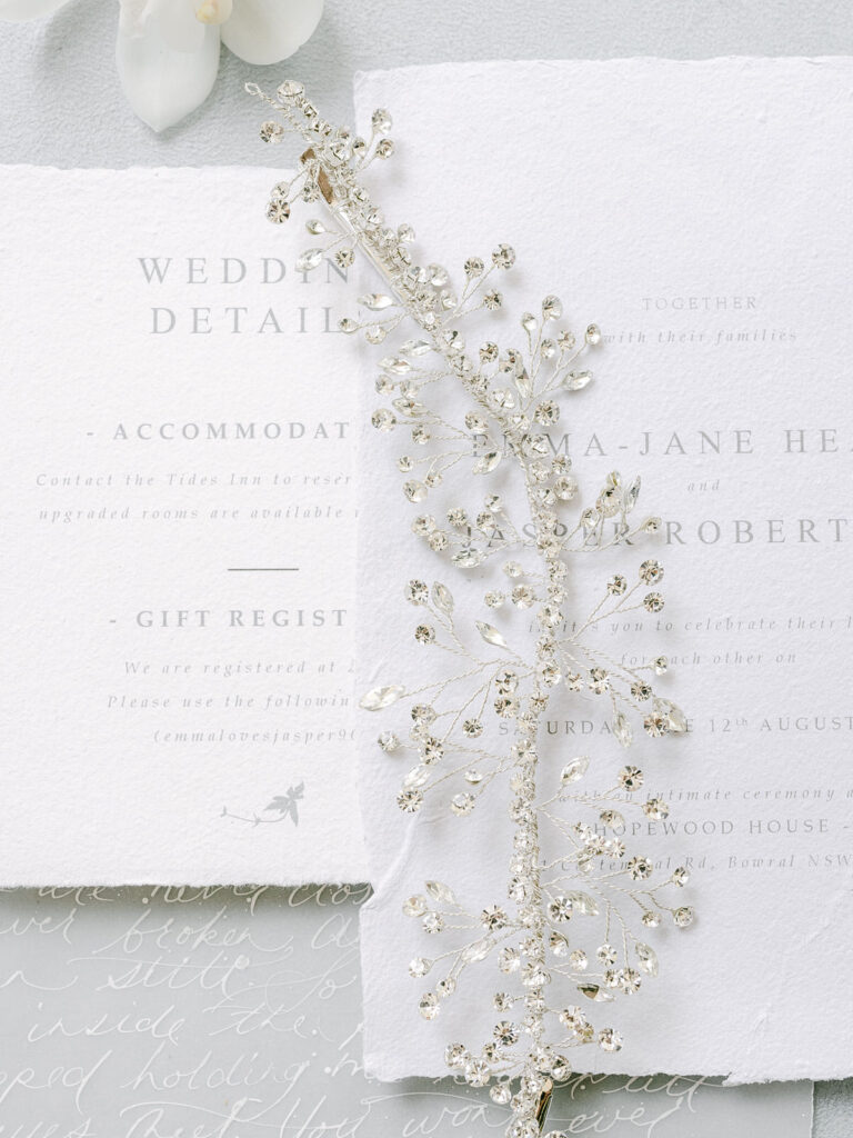 The White Collection bridal hair accessory with pearls laying on the wedding invitation