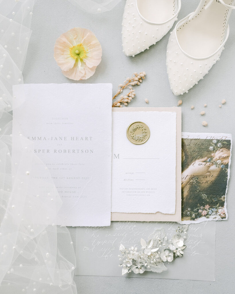 The White Collection bridal hair accessory with pearls laying on the wedding invitation with Bella Belle Shoes